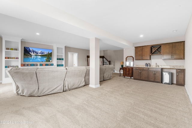 living room featuring light colored carpet, built in features, and sink