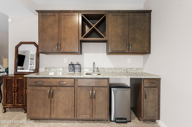 kitchen with light stone counters, sink, and dark brown cabinets