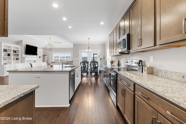 kitchen featuring dark wood-type flooring, hanging light fixtures, light stone counters, stainless steel appliances, and a chandelier