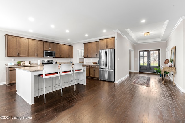 kitchen featuring french doors, a breakfast bar, stainless steel appliances, dark wood-type flooring, and a kitchen island