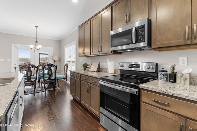 kitchen with dark hardwood / wood-style flooring, light stone counters, ornamental molding, stainless steel appliances, and an inviting chandelier