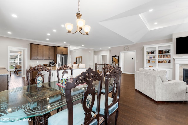 dining space with a fireplace, crown molding, dark wood-type flooring, and an inviting chandelier