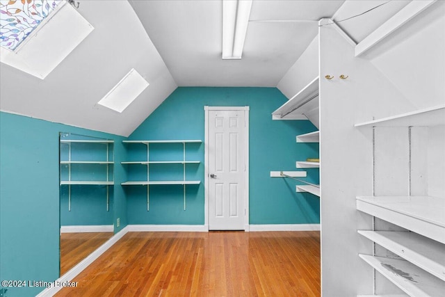 walk in closet with vaulted ceiling with skylight and wood finished floors