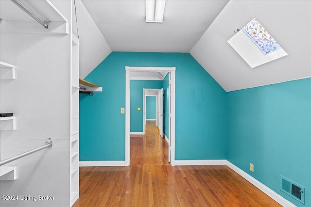 bonus room featuring vaulted ceiling with skylight, visible vents, baseboards, and wood finished floors