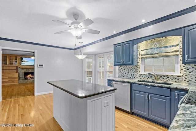 kitchen featuring a kitchen island, ornamental molding, blue cabinets, stainless steel dishwasher, and a sink