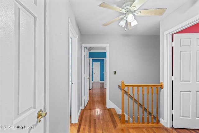 hall with baseboards, wood finished floors, and an upstairs landing