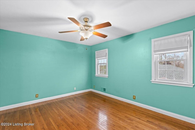 spare room featuring baseboards, ceiling fan, visible vents, and hardwood / wood-style floors