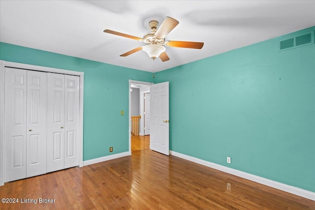 unfurnished bedroom featuring a closet, visible vents, a ceiling fan, wood finished floors, and baseboards