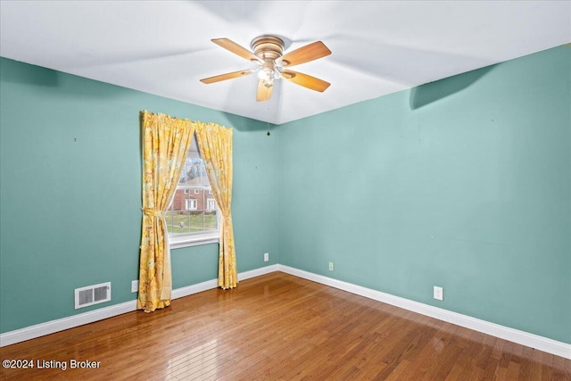 unfurnished room with ceiling fan, hardwood / wood-style flooring, visible vents, and baseboards