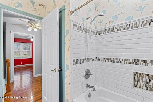 bathroom with wallpapered walls, baseboards, a ceiling fan, wood finished floors, and bathtub / shower combination