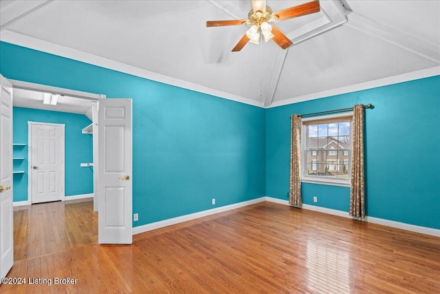 empty room featuring lofted ceiling, wood finished floors, and baseboards