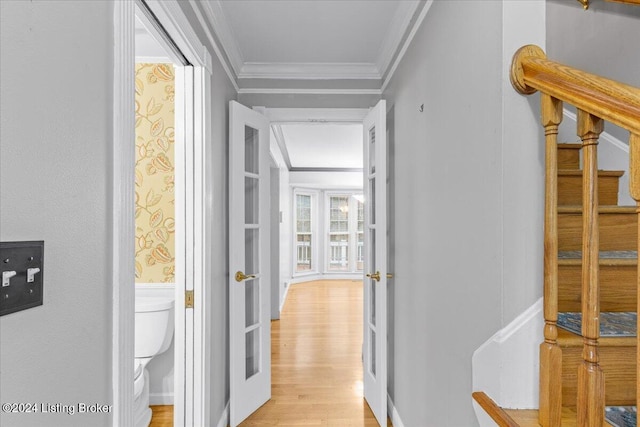 hallway with ornamental molding, stairway, and light wood-style flooring