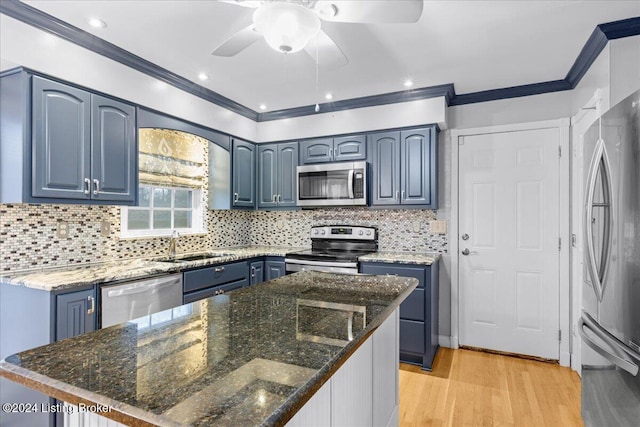 kitchen featuring blue cabinets, a sink, light wood-style floors, ornamental molding, and appliances with stainless steel finishes