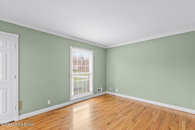 unfurnished room featuring ornamental molding, visible vents, baseboards, and wood finished floors