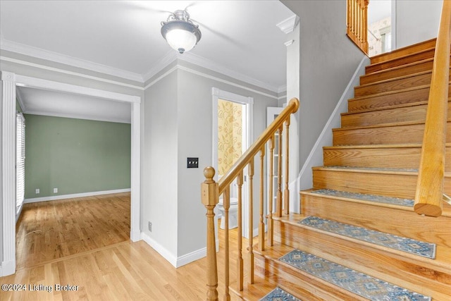 stairway with baseboards, ornamental molding, and wood finished floors