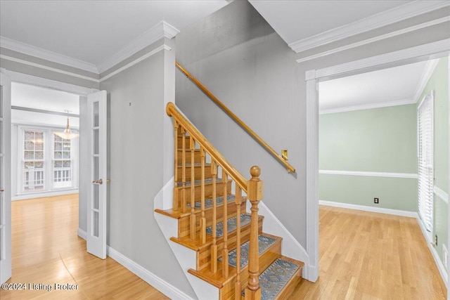 stairs with crown molding, baseboards, and wood finished floors