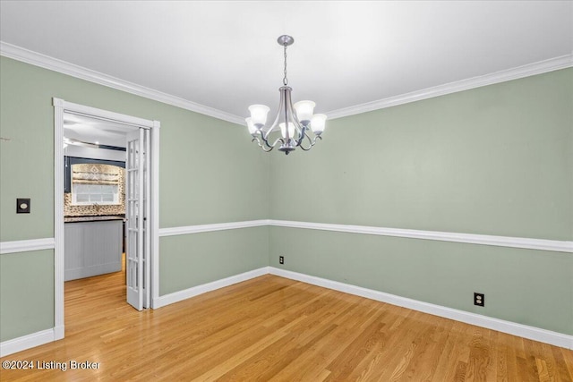 unfurnished dining area with light wood-style floors, a notable chandelier, ornamental molding, and baseboards