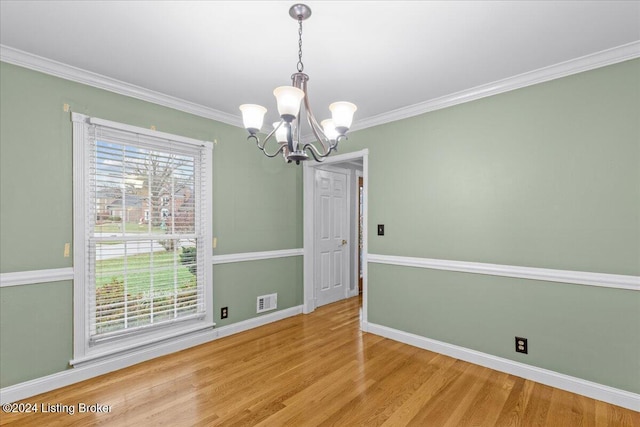 unfurnished dining area with baseboards, visible vents, wood finished floors, and ornamental molding