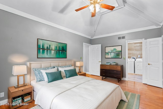 bedroom featuring baseboards, visible vents, wood finished floors, vaulted ceiling with beams, and separate washer and dryer