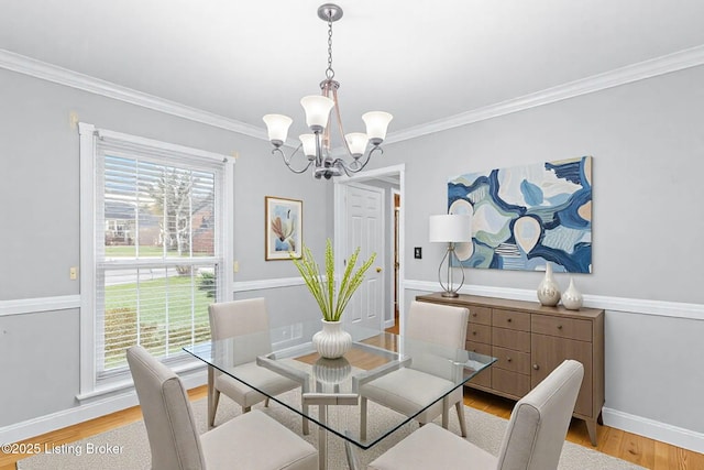 dining room with baseboards, ornamental molding, light wood-style flooring, and an inviting chandelier