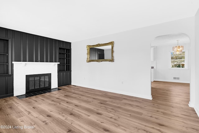 unfurnished living room with a brick fireplace and light hardwood / wood-style flooring