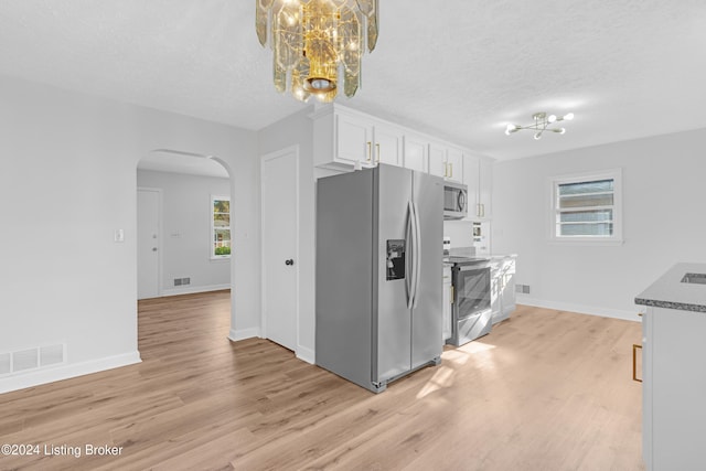 kitchen with light hardwood / wood-style flooring, a textured ceiling, white cabinetry, stainless steel appliances, and a chandelier