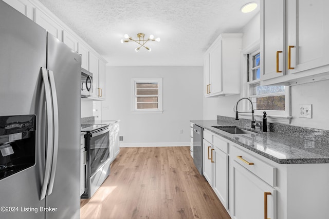 kitchen with white cabinets, appliances with stainless steel finishes, a textured ceiling, and sink