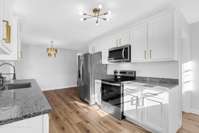 kitchen featuring an inviting chandelier, sink, light wood-type flooring, white cabinetry, and stainless steel appliances