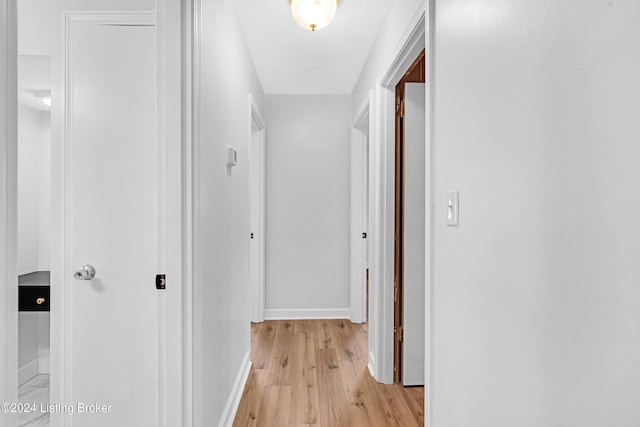 hall with a textured ceiling and light hardwood / wood-style flooring