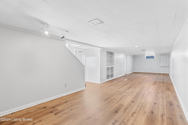 basement with built in shelves, track lighting, and light wood-type flooring