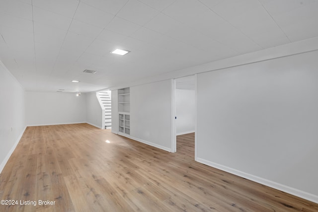 basement with built in shelves and light wood-type flooring