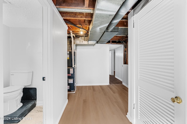 basement with light hardwood / wood-style floors and heating unit