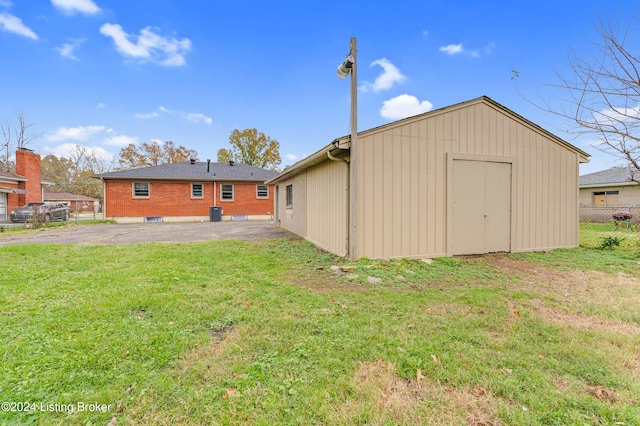 back of house featuring a lawn, a storage shed, and a patio