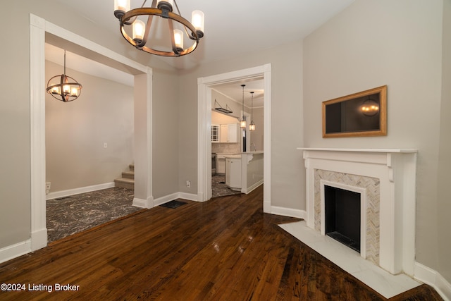 unfurnished living room featuring a fireplace, dark wood-type flooring, and a notable chandelier