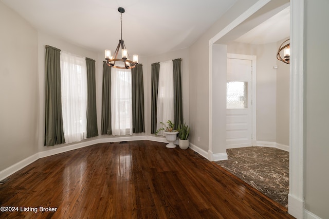 interior space featuring a healthy amount of sunlight, dark hardwood / wood-style floors, and an inviting chandelier