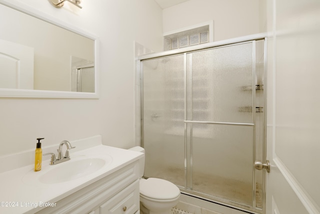 bathroom with tile patterned flooring, vanity, a shower with shower door, and toilet