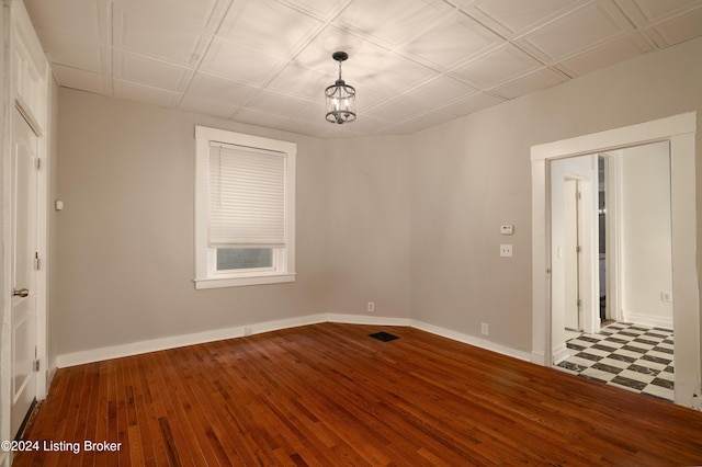 spare room featuring an inviting chandelier and hardwood / wood-style flooring