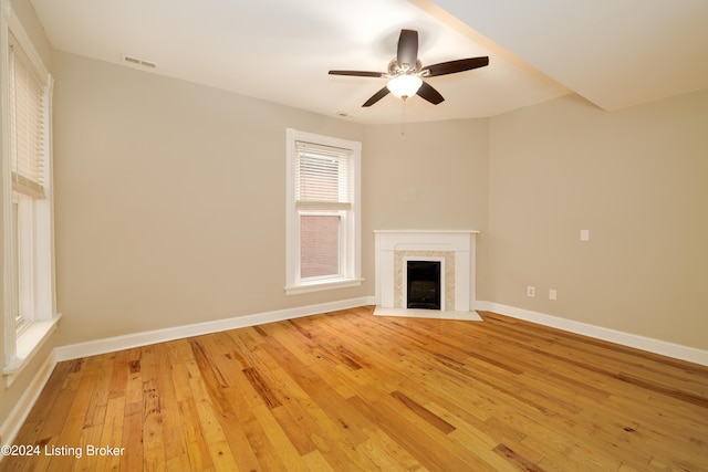 unfurnished living room featuring ceiling fan, a premium fireplace, and light hardwood / wood-style flooring