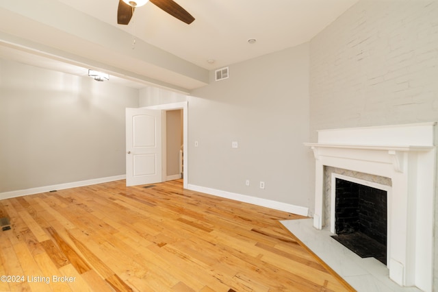 unfurnished living room with a high end fireplace, hardwood / wood-style floors, and ceiling fan