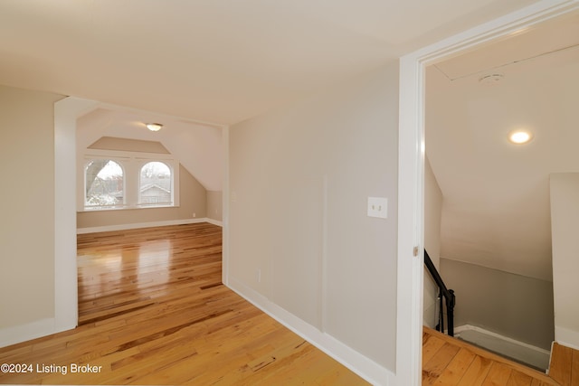 additional living space with light hardwood / wood-style floors and vaulted ceiling