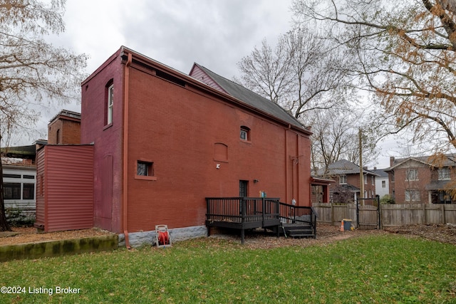 rear view of house with a lawn and a wooden deck