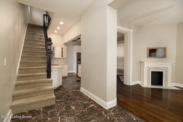 stairway with a high end fireplace and wood-type flooring