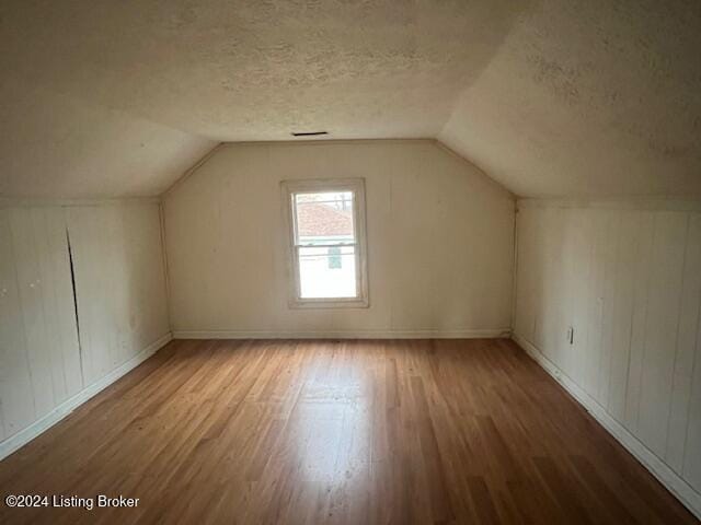 bonus room featuring a textured ceiling, lofted ceiling, and hardwood / wood-style flooring