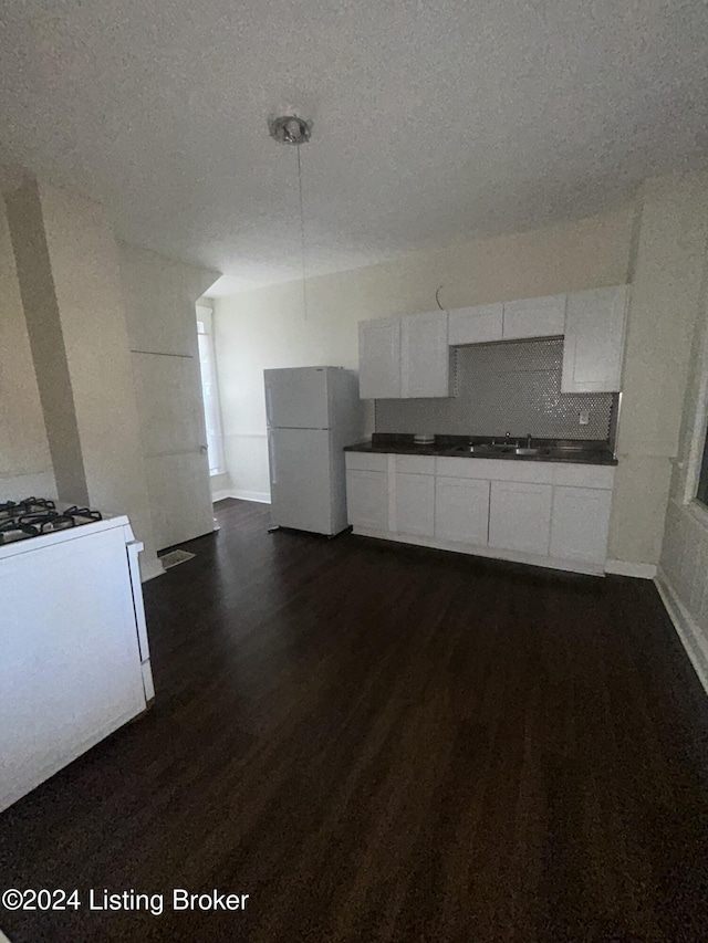 kitchen with white appliances, white cabinets, sink, a textured ceiling, and dark hardwood / wood-style flooring