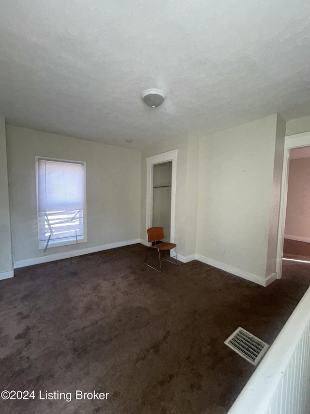 carpeted empty room with a textured ceiling