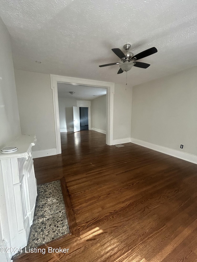 empty room with dark hardwood / wood-style floors, ceiling fan, and a textured ceiling