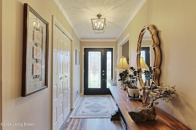 entrance foyer featuring hardwood / wood-style flooring, ornamental molding, a textured ceiling, and an inviting chandelier