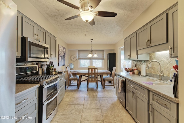 kitchen featuring sink, hanging light fixtures, a textured ceiling, tasteful backsplash, and stainless steel appliances