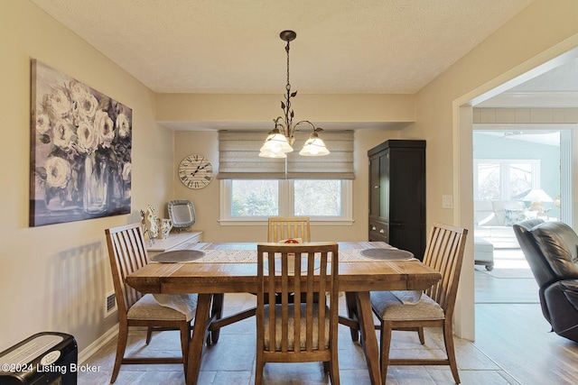 dining space with a notable chandelier, a textured ceiling, and a wealth of natural light