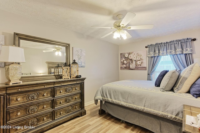 bedroom with a textured ceiling, light hardwood / wood-style flooring, and ceiling fan